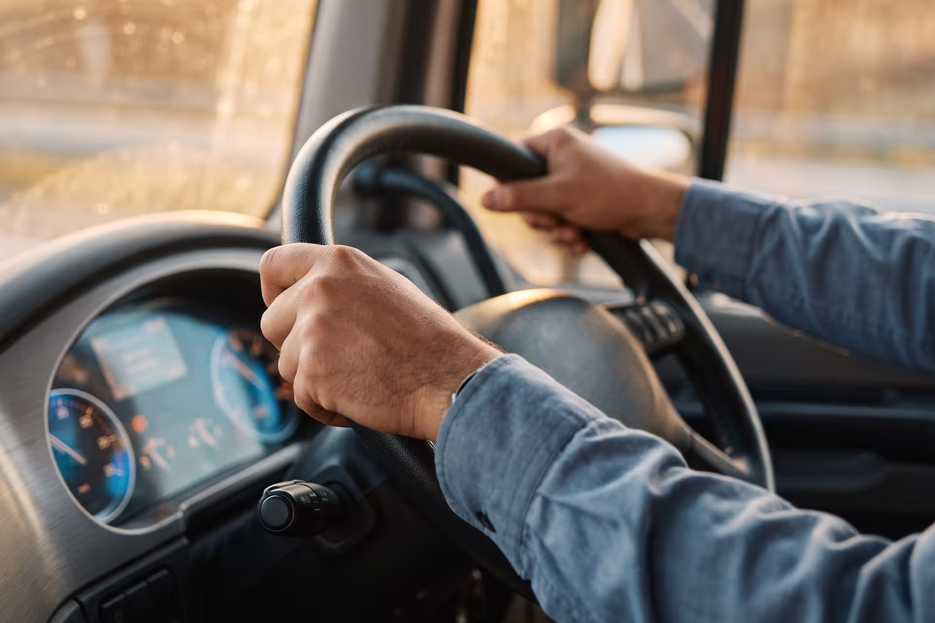 Close-up of a driver's hands gripping the steering wheel inside a truck cab