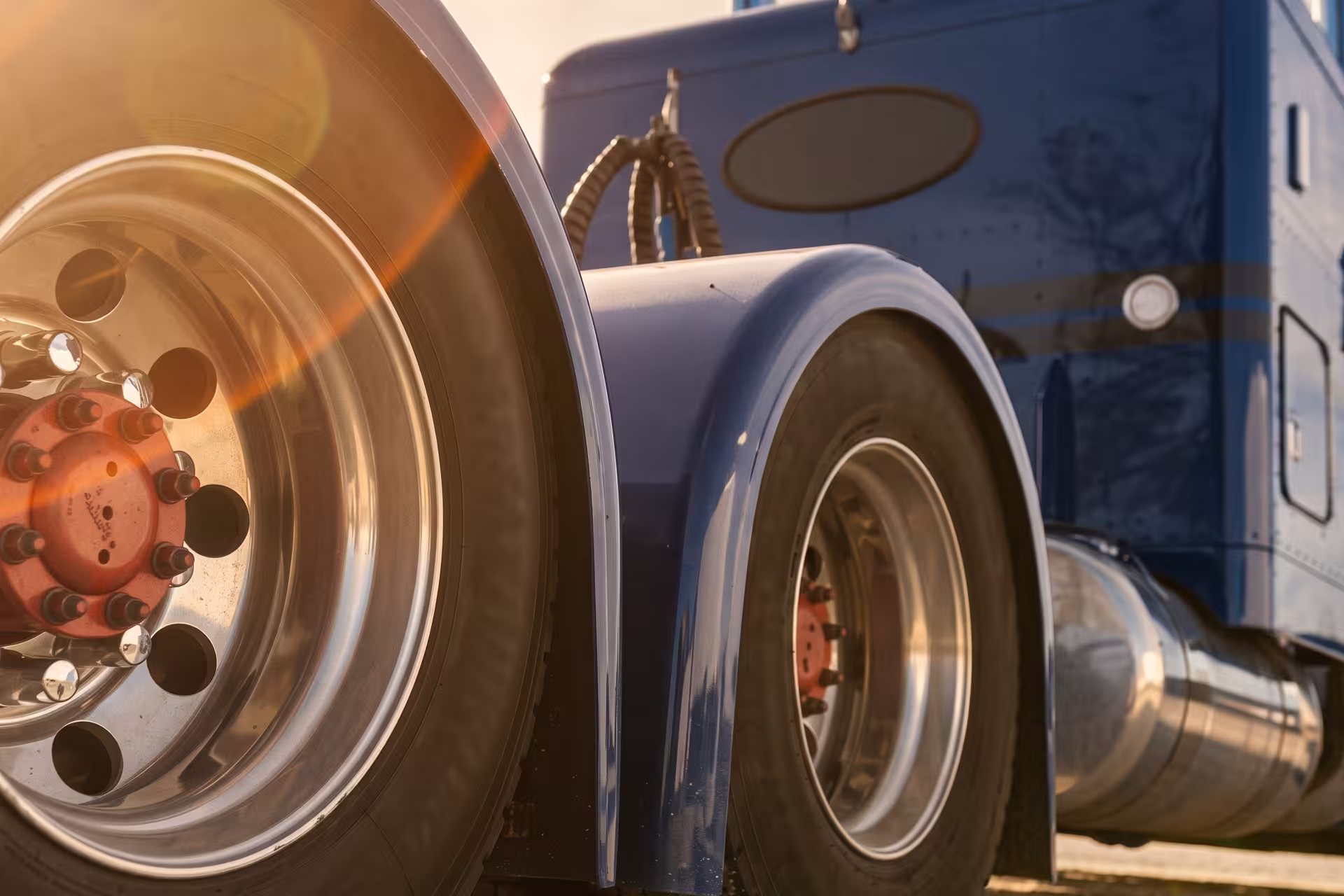 Close-up of a semi-truck's rear wheels and cab in golden light