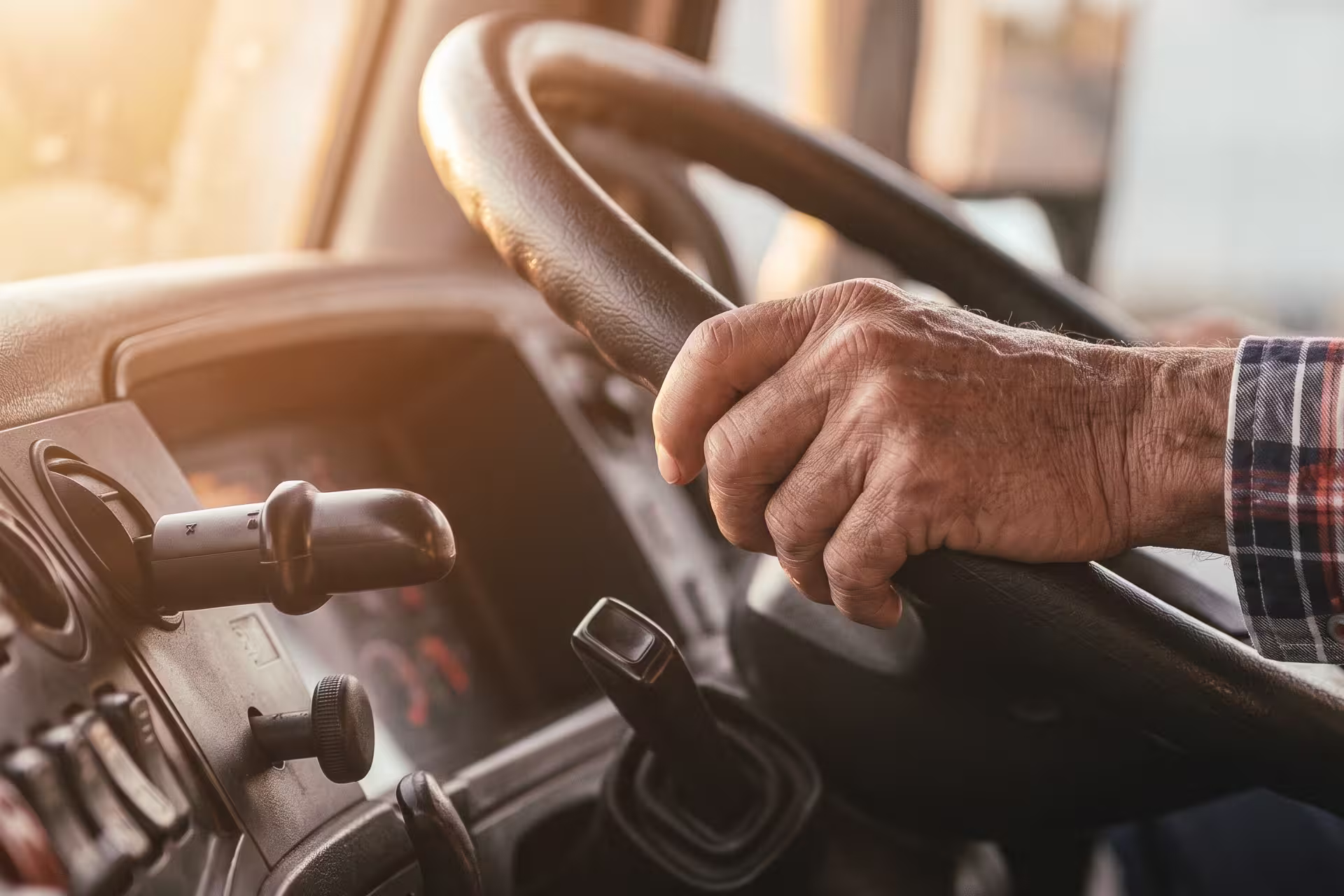 Close-up of a driver's hand gripping the gear shifter inside a truck cab