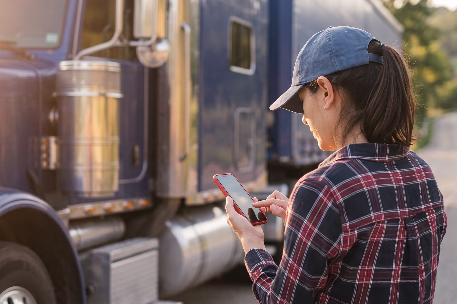 Driver checking a smartphone in front of a parked semi-truck