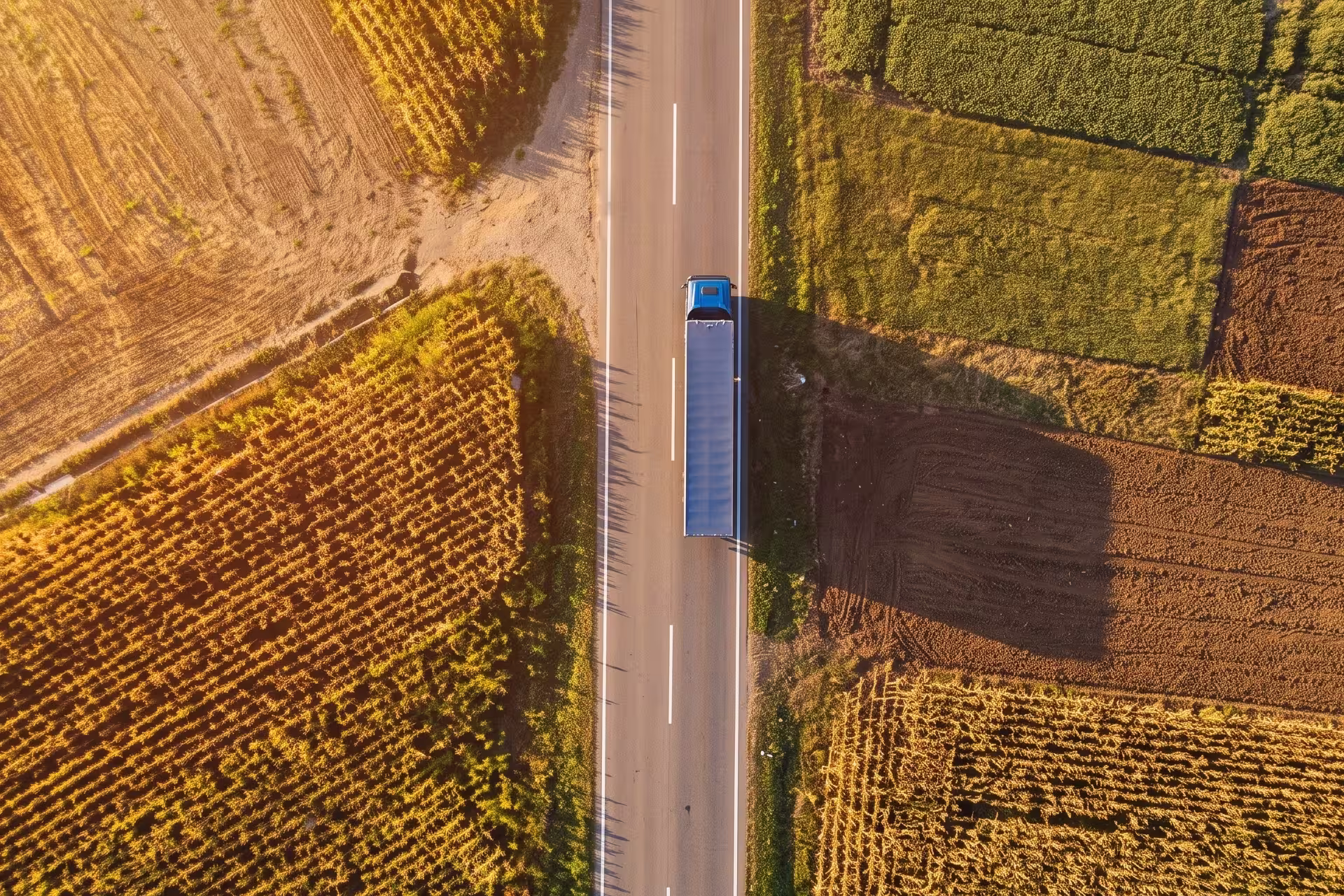 Aerial top-down view of a truck driving on a road between farm fields
