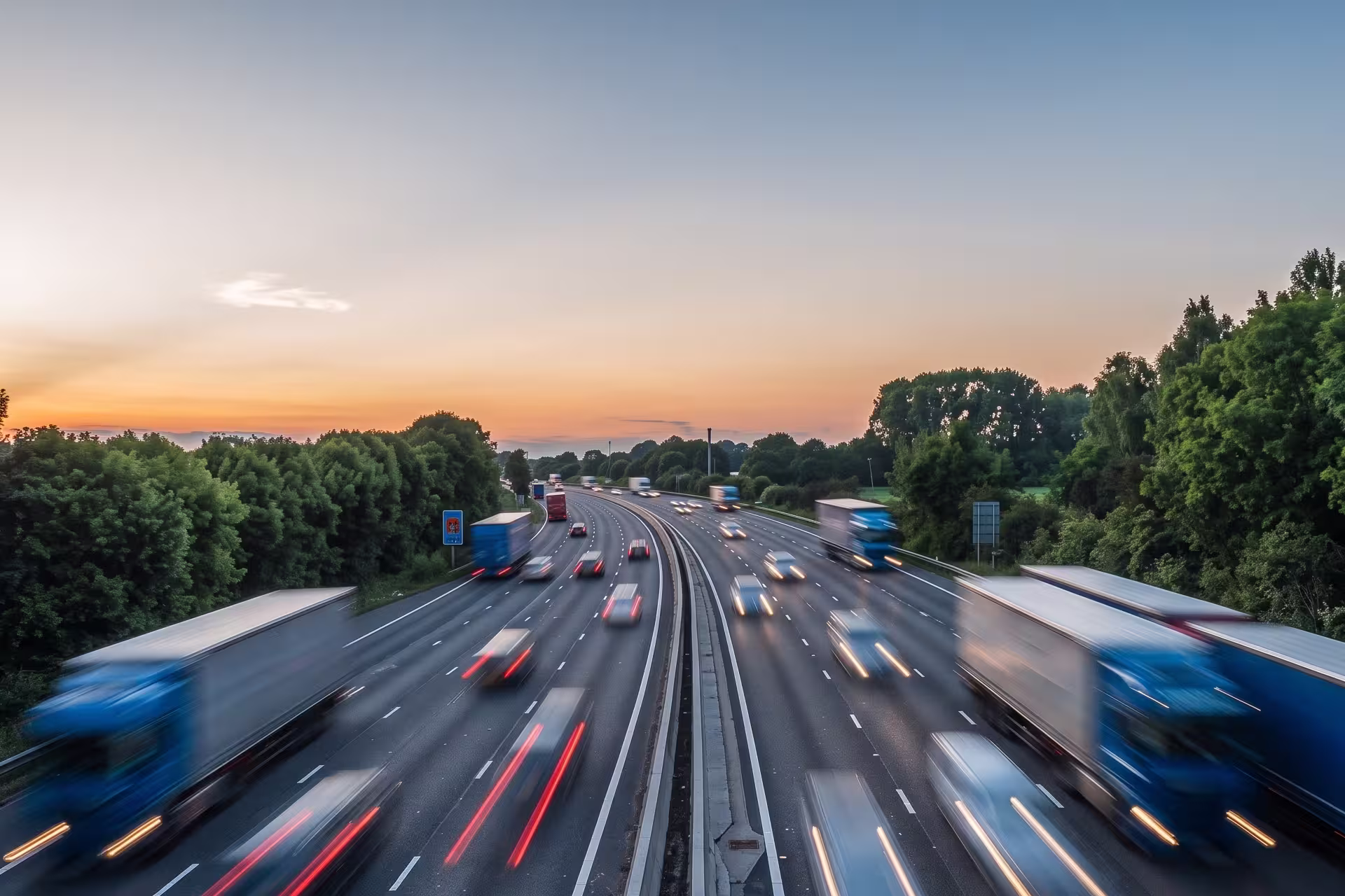 Aerial view of highway traffic with semi-trucks and cars in motion at dusk