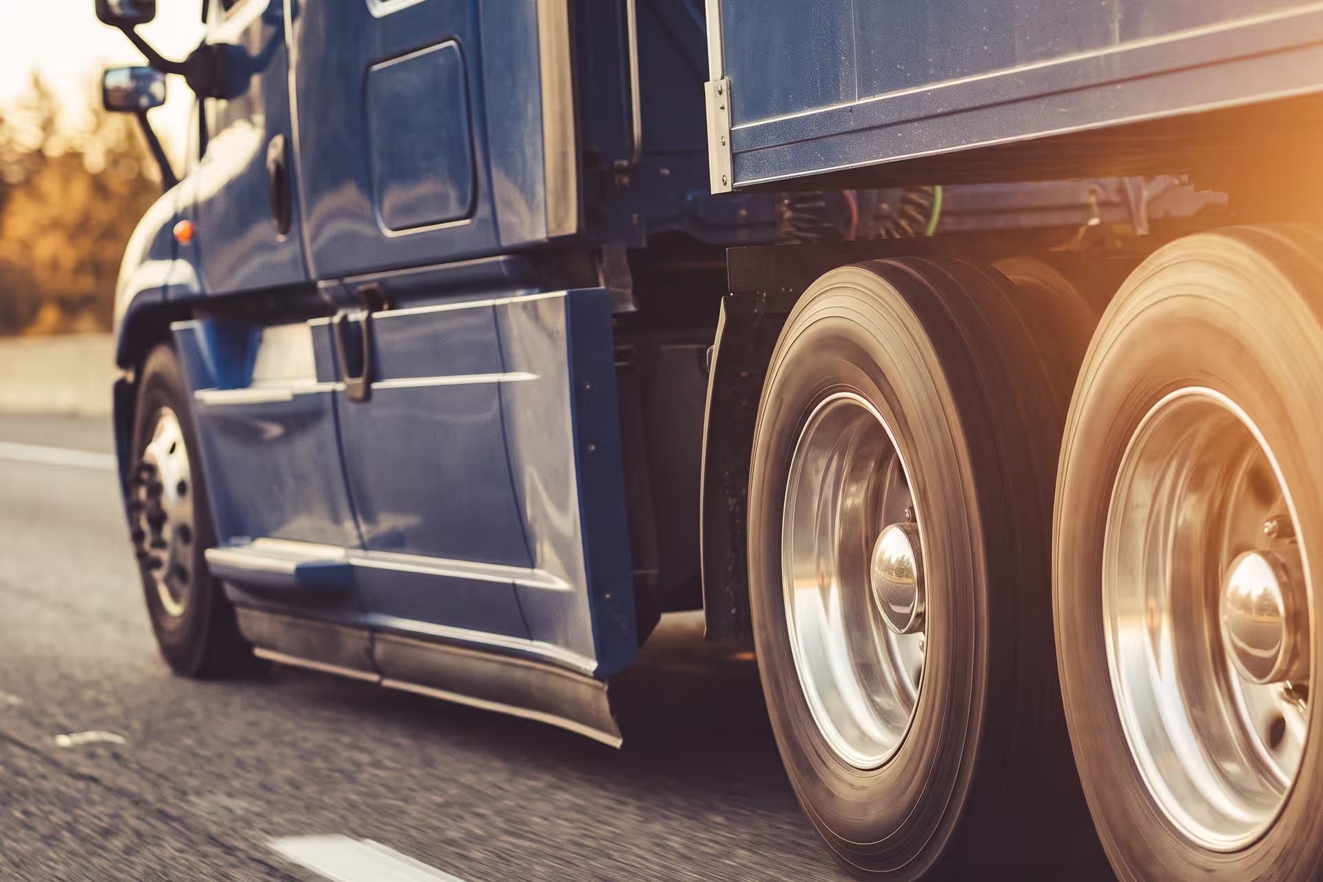 Close-up of a semi-truck's rear wheels and chassis in motion on the highway