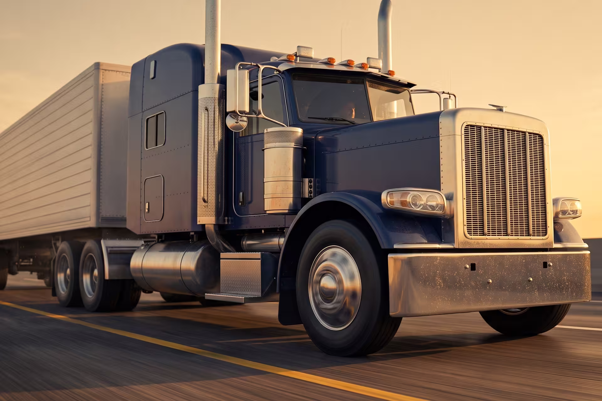 Close-up front view of a semi-truck and trailer on the road at sunset with driver visible