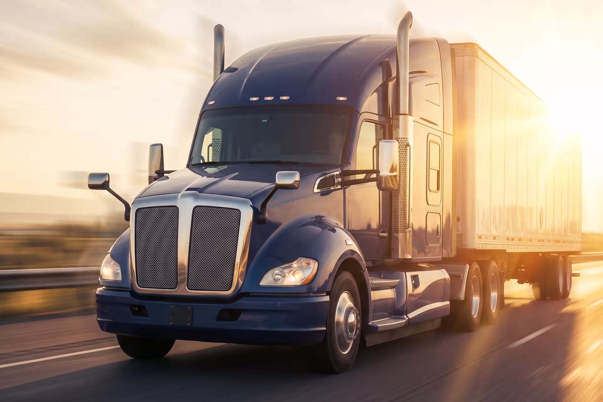 Semi-truck with trailer driving on a highway at sunrise