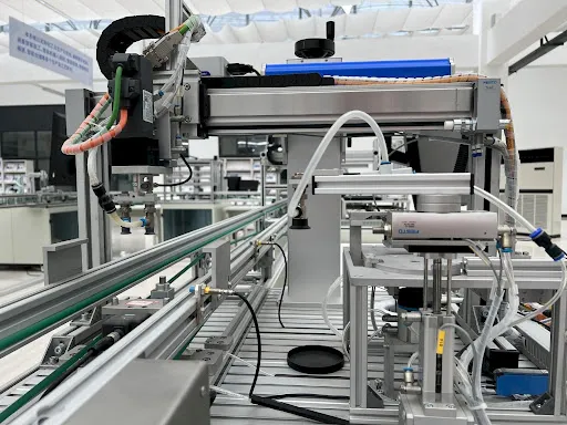 Industrial automation equipment with conveyor rails and robotic components in a clean factory setting.