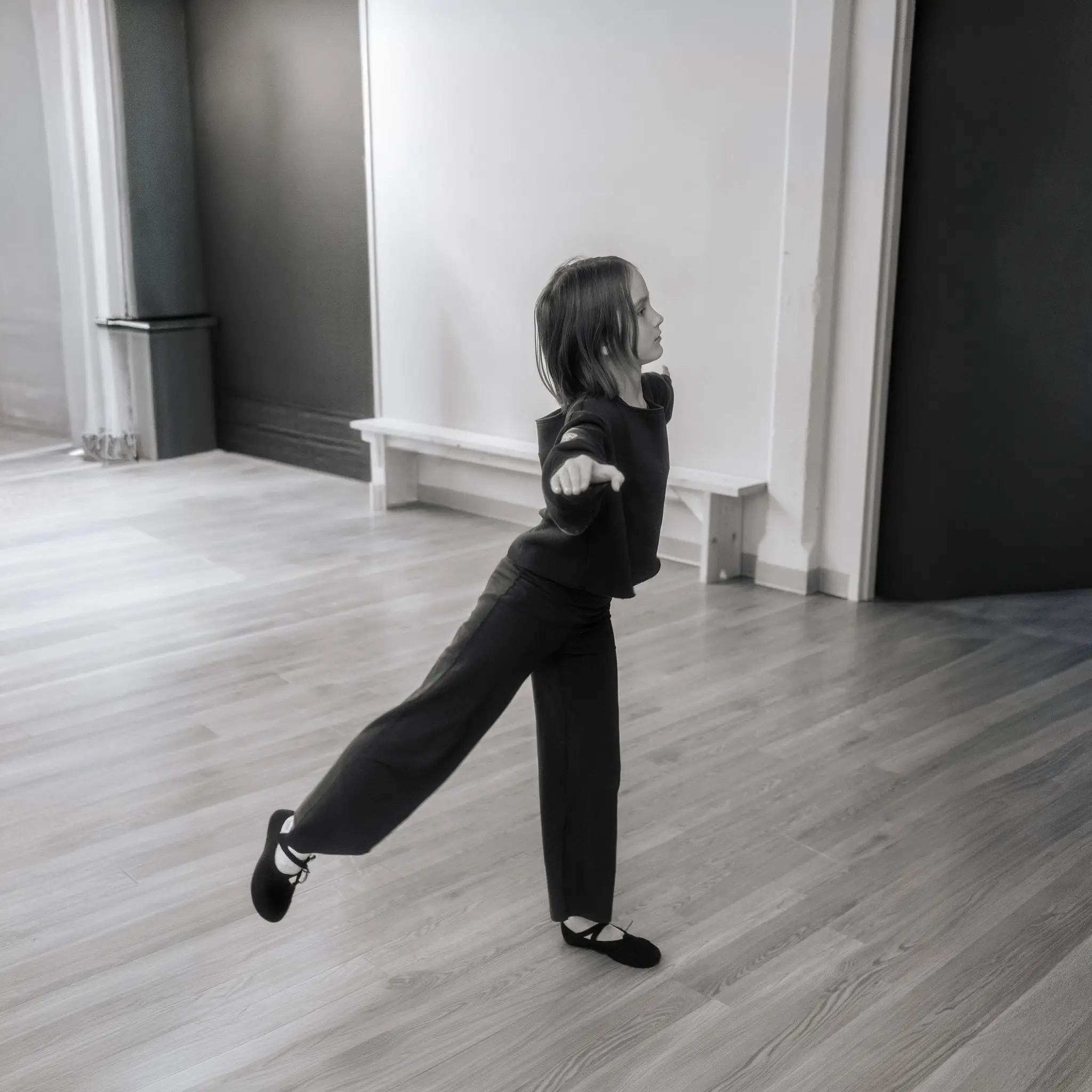 Jeune danseuse en équilibre sur une jambe, bras tendu vers l'avant, pendant un cours de Lyrique Fusion à l'École de Danse M3 de Cowansville.