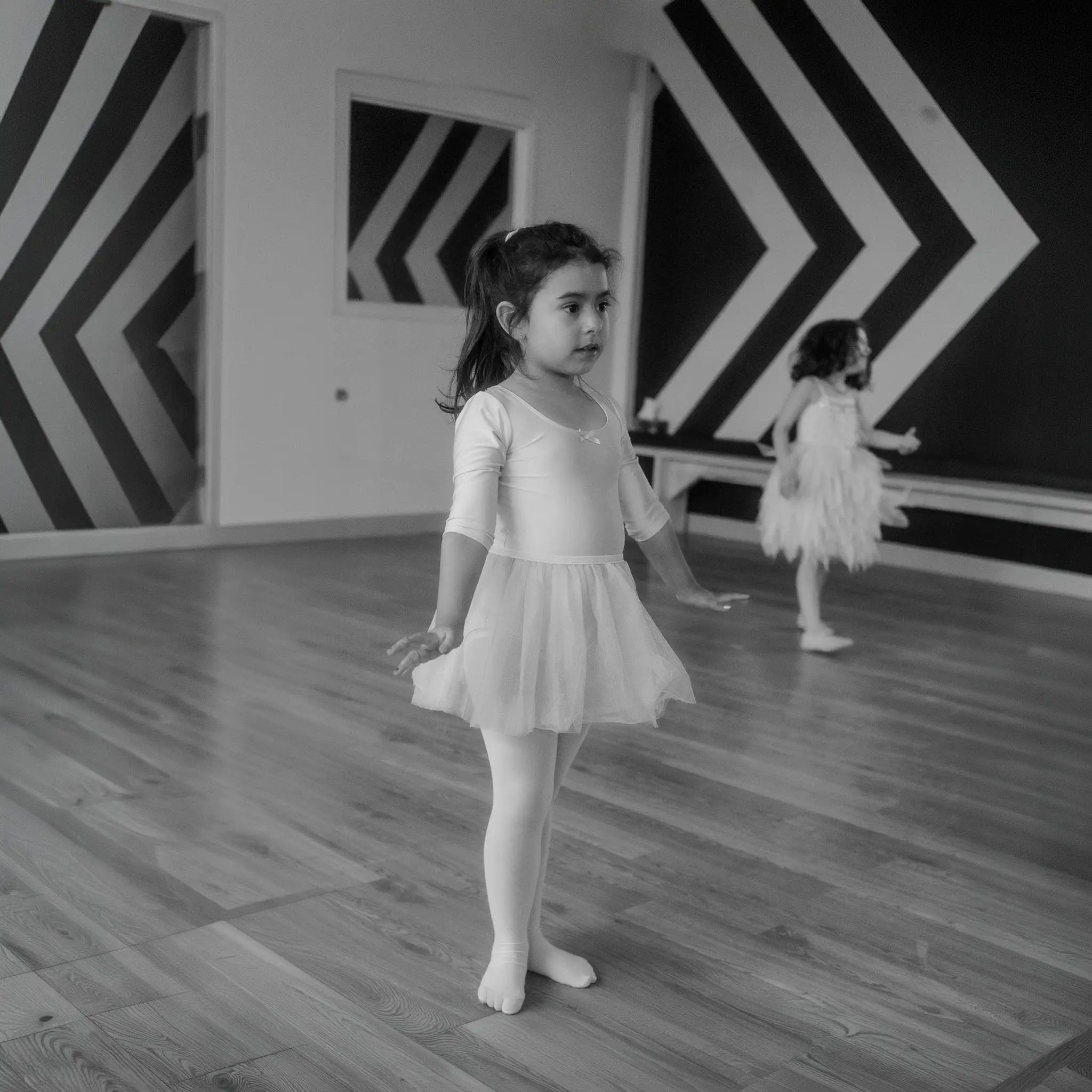 Fillette en justaucorps et tutu devant le mur à chevrons du studio, pendant un cours de ballet à l'École de Danse M3 de Cowansville.