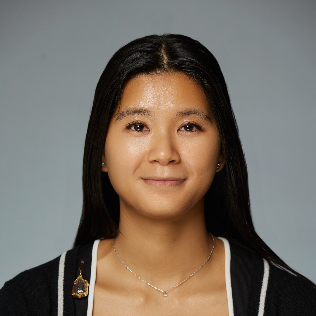 Smiling woman with long black hair wearing a black and white sweater and a silver necklace.