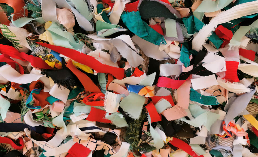 Close-up of colorful torn fabric scraps in various patterns and colors overlapping each other.
