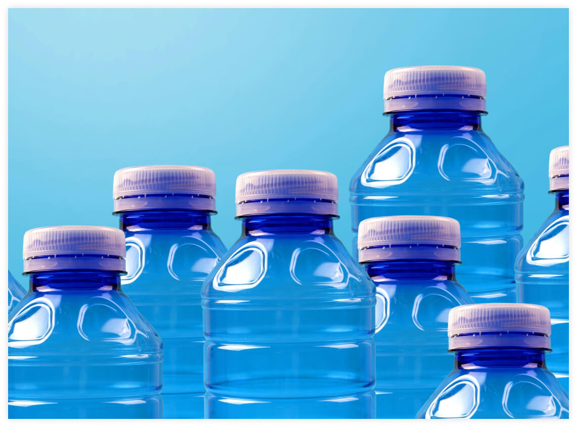 Group of blue plastic water bottles with white caps against a light blue background.