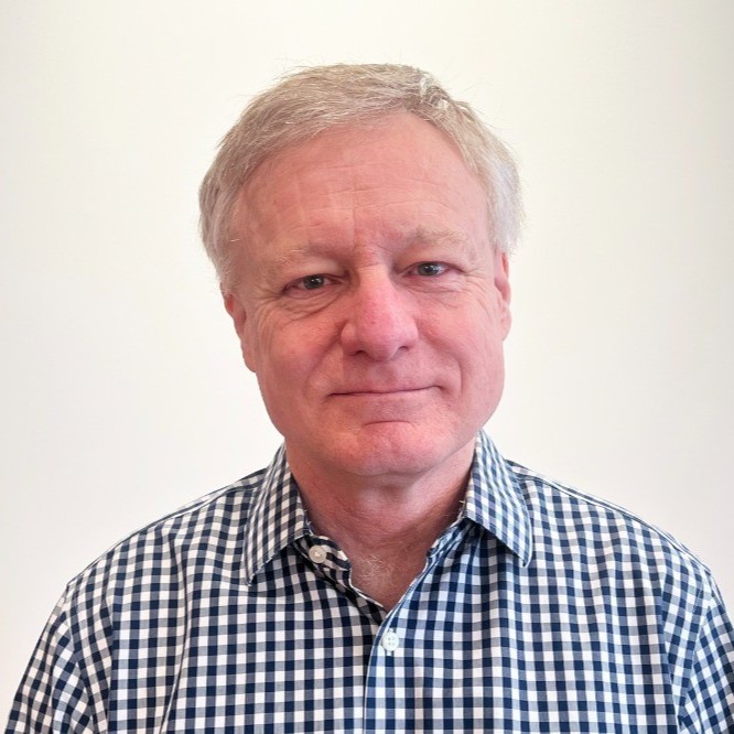 Middle-aged man with light hair wearing a blue and white checkered shirt against a plain background.