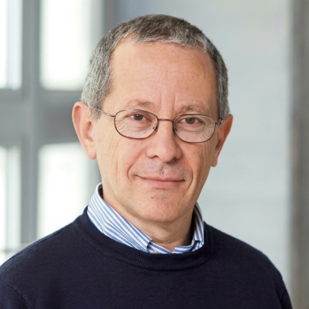 Portrait of a middle-aged man wearing glasses and a navy sweater over a striped shirt.