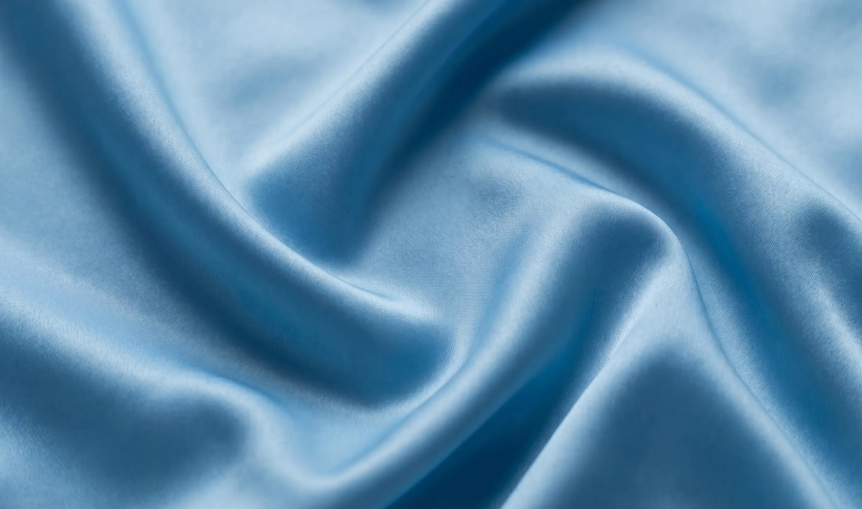 Smooth flowing light blue satin fabric with soft folds and sheen.