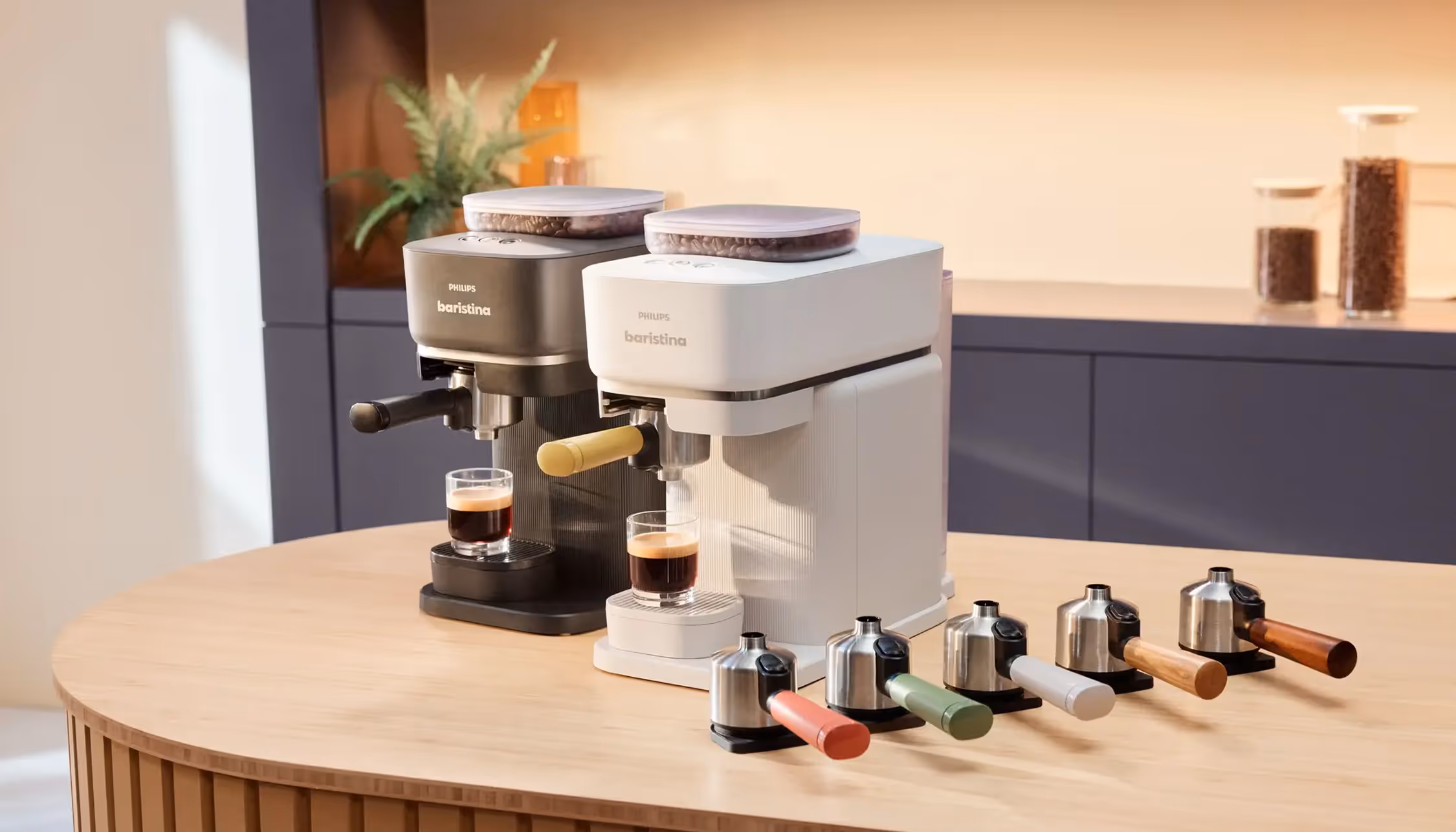 Two Philips Baristina espresso machines with coffee beans and six colored handles on a wooden table.