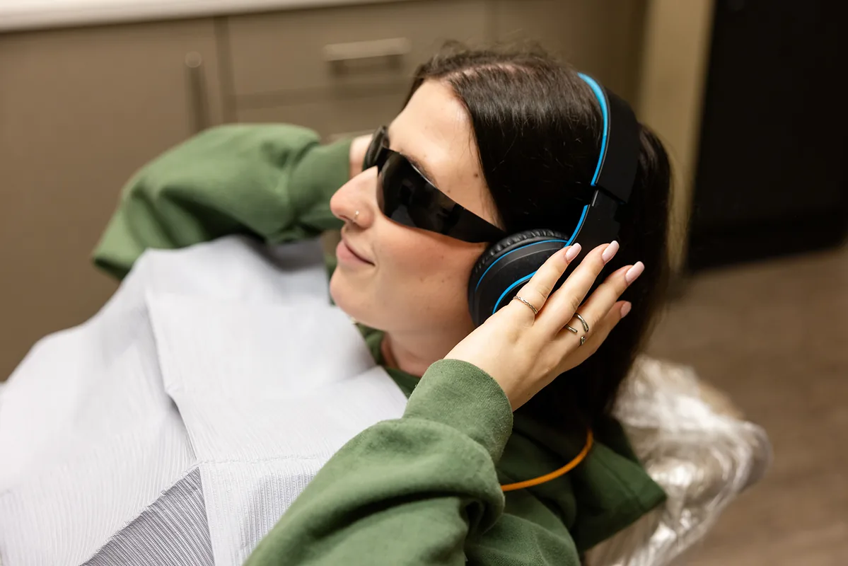 A patient in headphones and dark glasses settled back comfortably in the dental chair