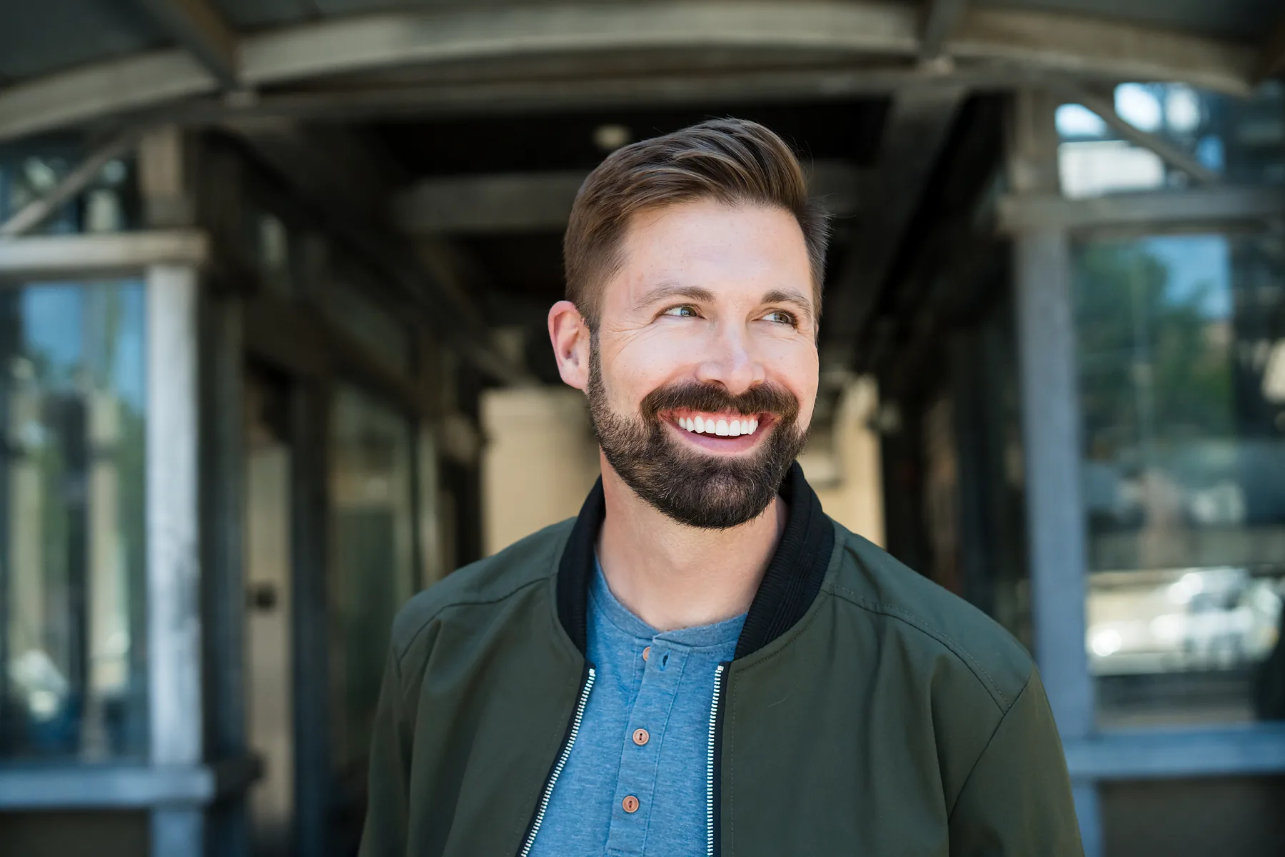 A man smiling on a city sidewalk, back to his ordinary day