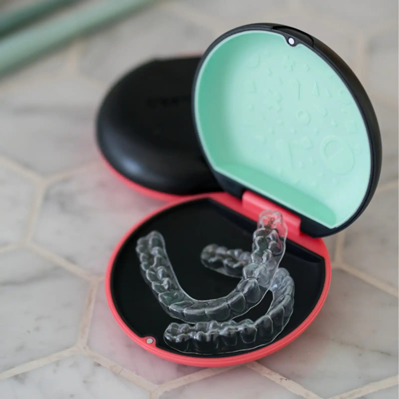 A pair of clear aligners in their open case on a bathroom counter