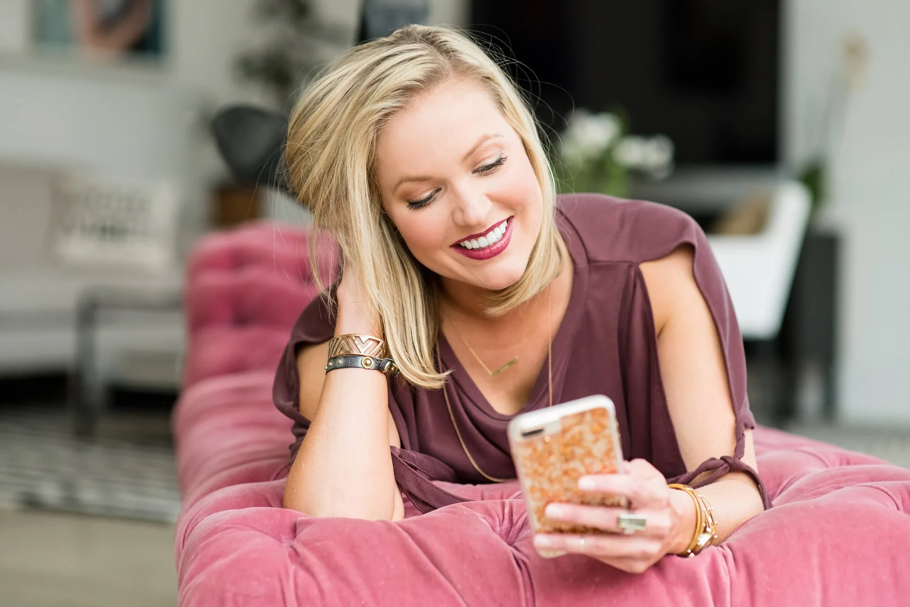 A woman relaxed at home on her couch, looking at her phone