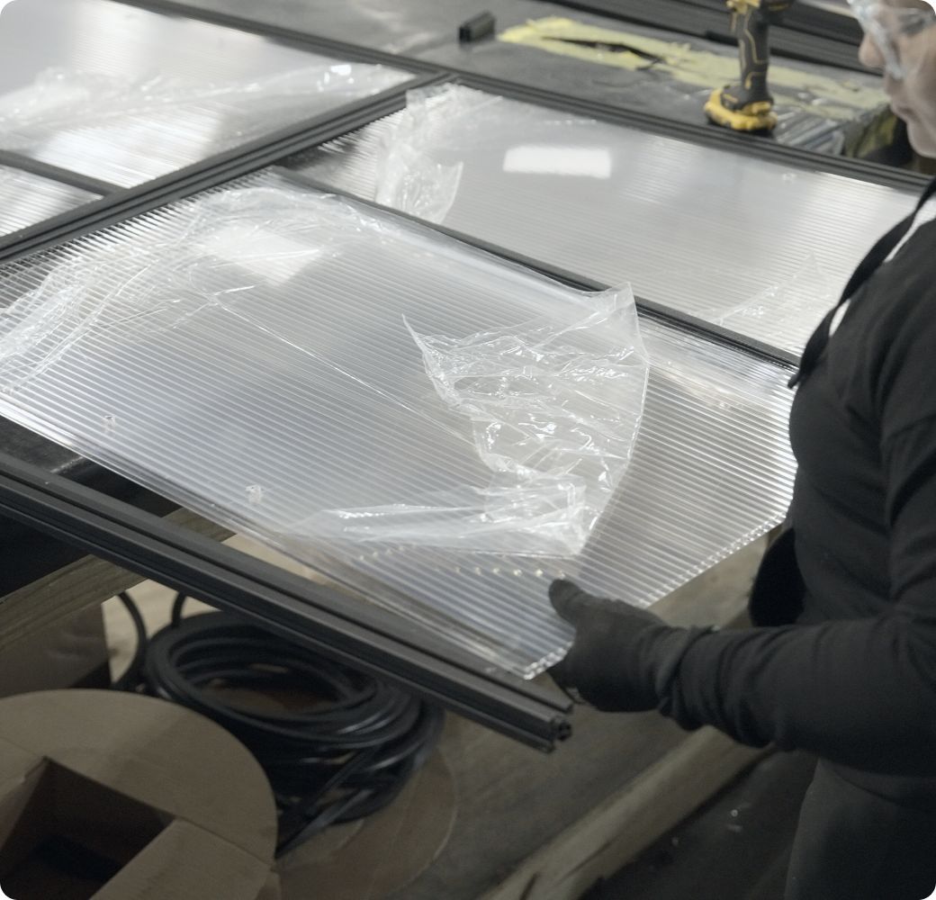 Technician handling a clear containment panel in the factory