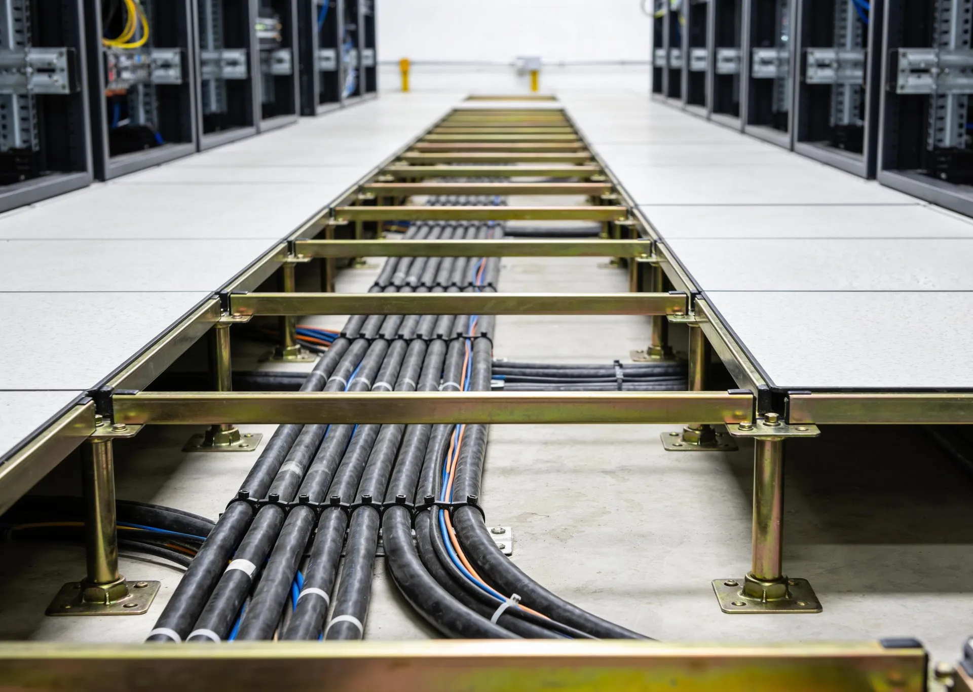 Raised access floor with cabling looking down an aisle between server racks