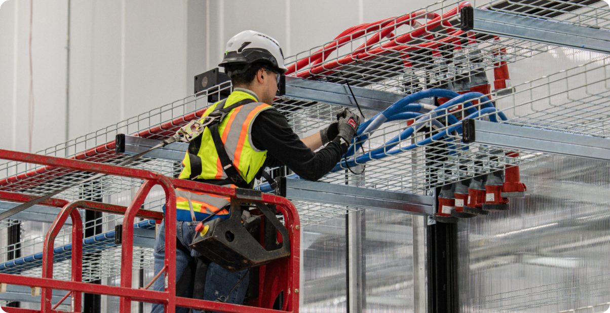 Electrician installing overhead cable tray from a lift