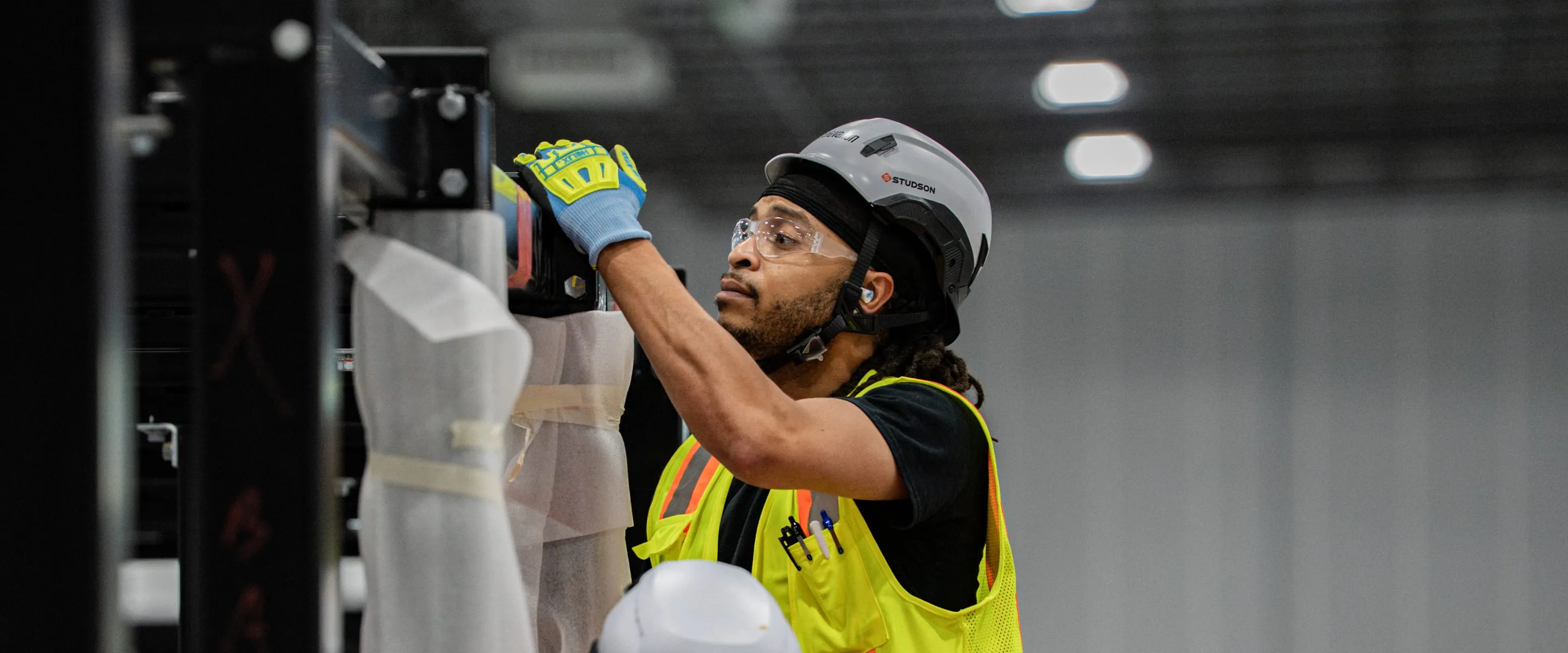An Accelevation technician in high-visibility gear working on data hall infrastructure