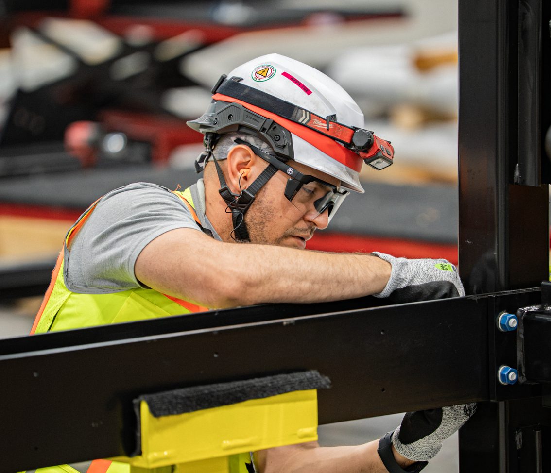 An Accelevation technician assembling a steel frame on the production floor