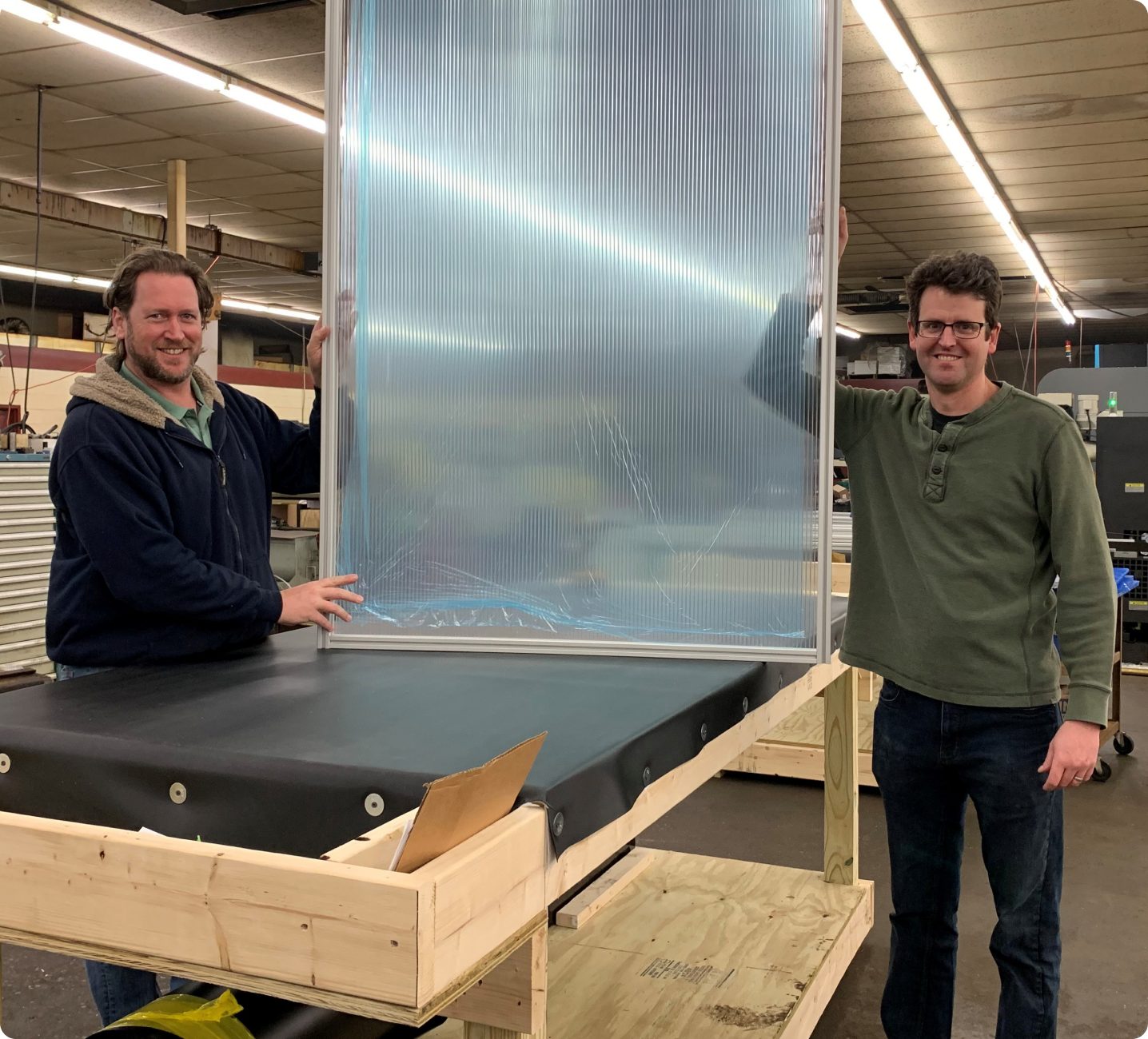 Two workers with a custom clear protective barrier