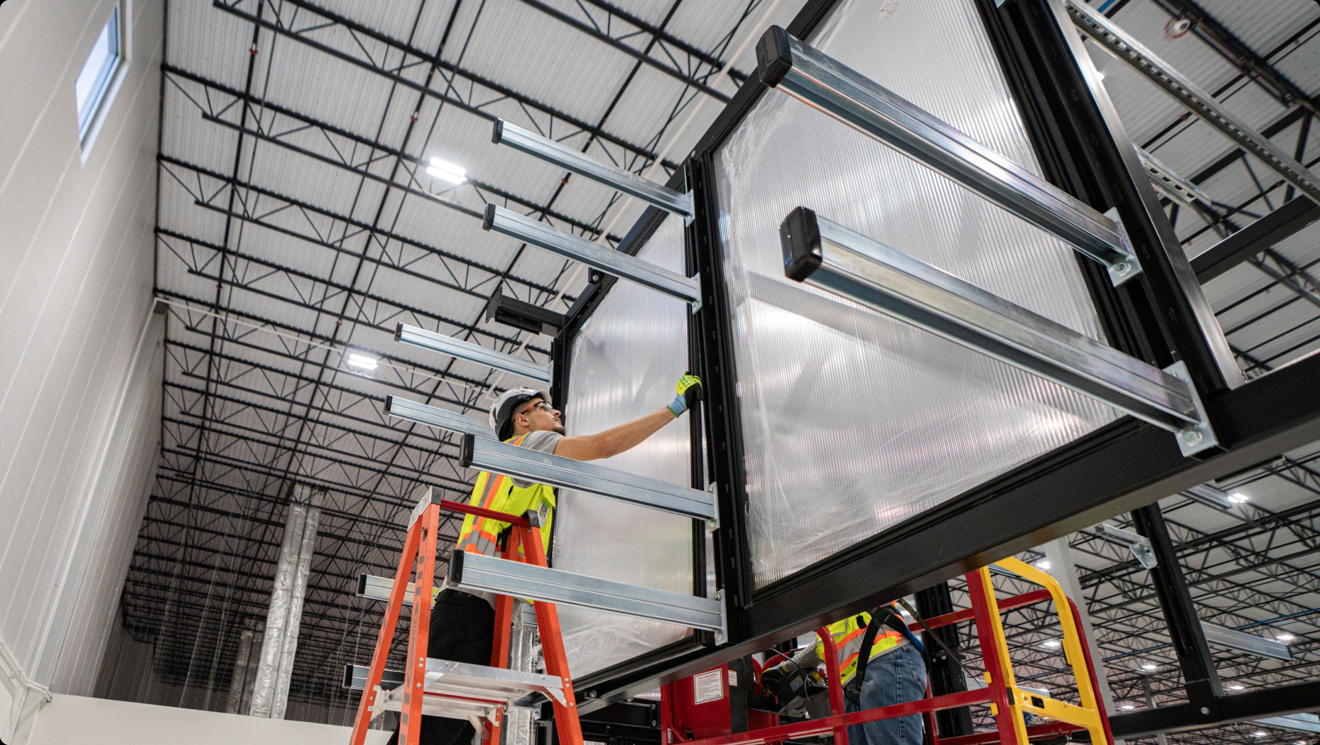 Technician installing an overhead containment panel from a ladder