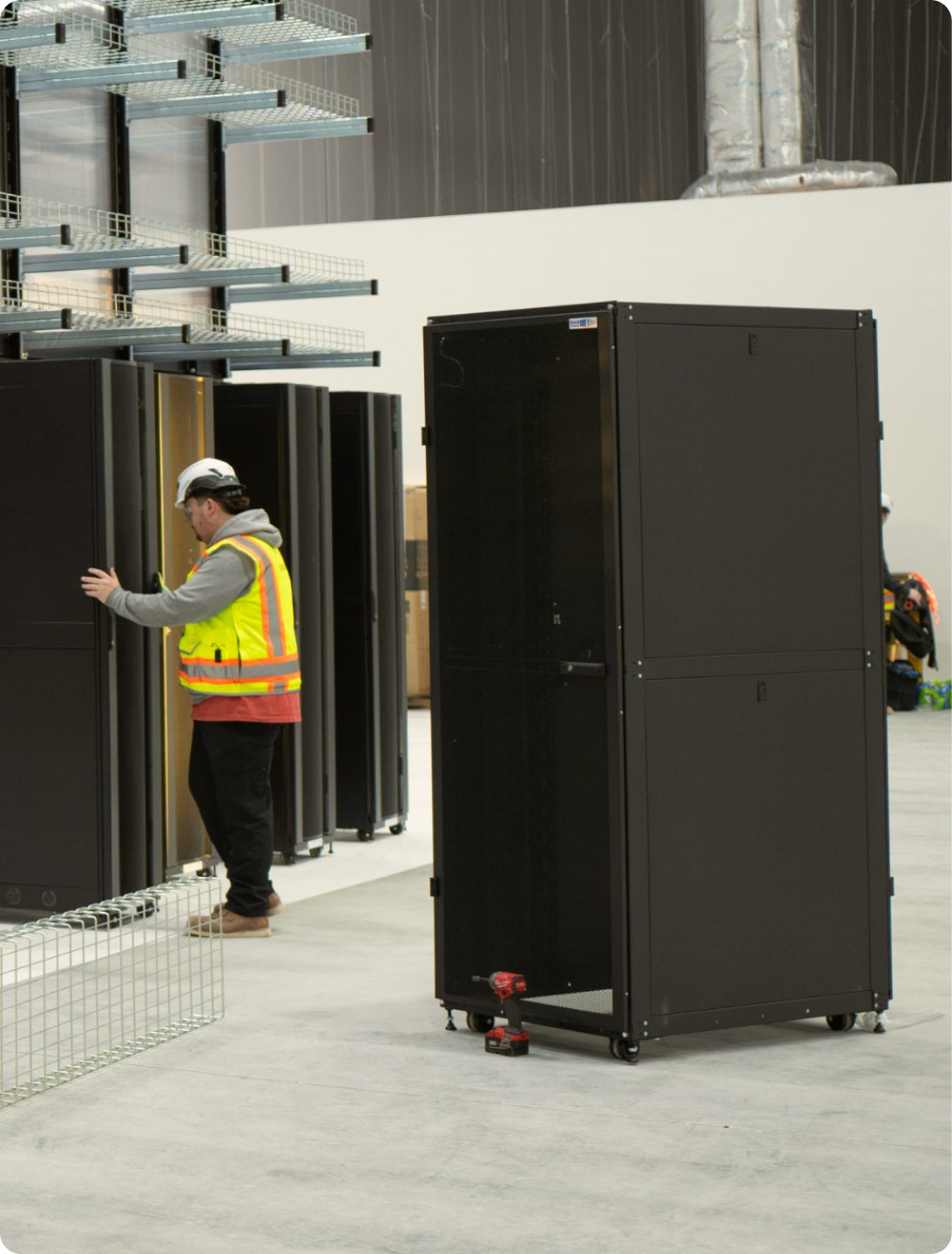 A technician in a hi-vis vest positioning equipment racks in the integration facility