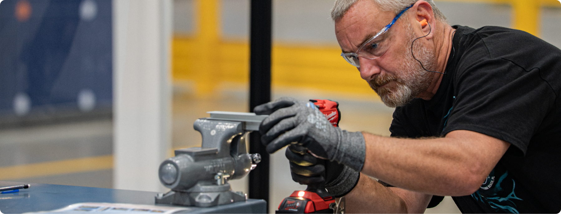 An Academy participant using a power tool on a component at a workstation