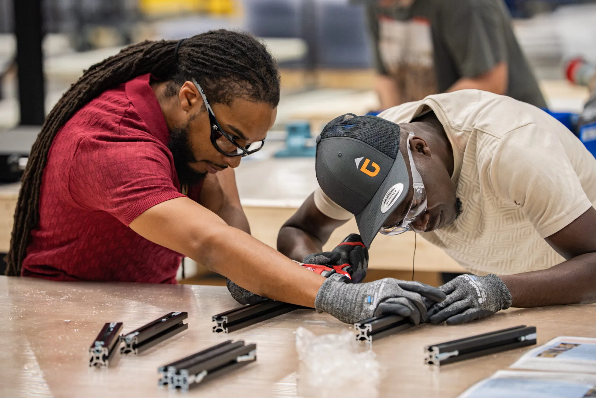 Two Accelevation Academy trainees assembling a steel frame at a workbench