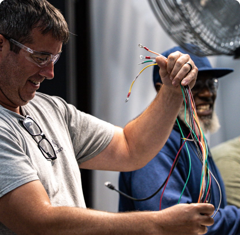 A trainee sorting coloured wiring alongside a colleague
