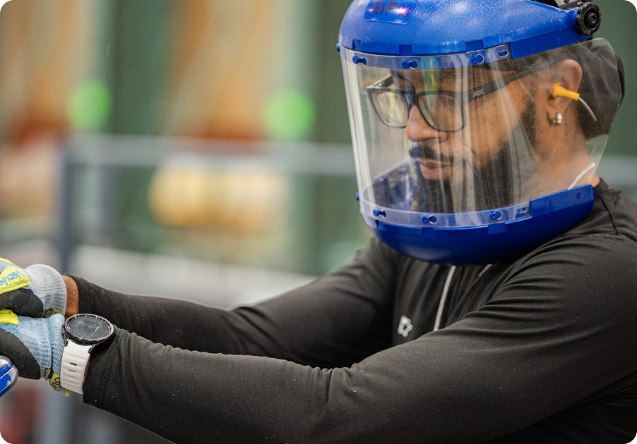 A team member wearing a blue welding face shield