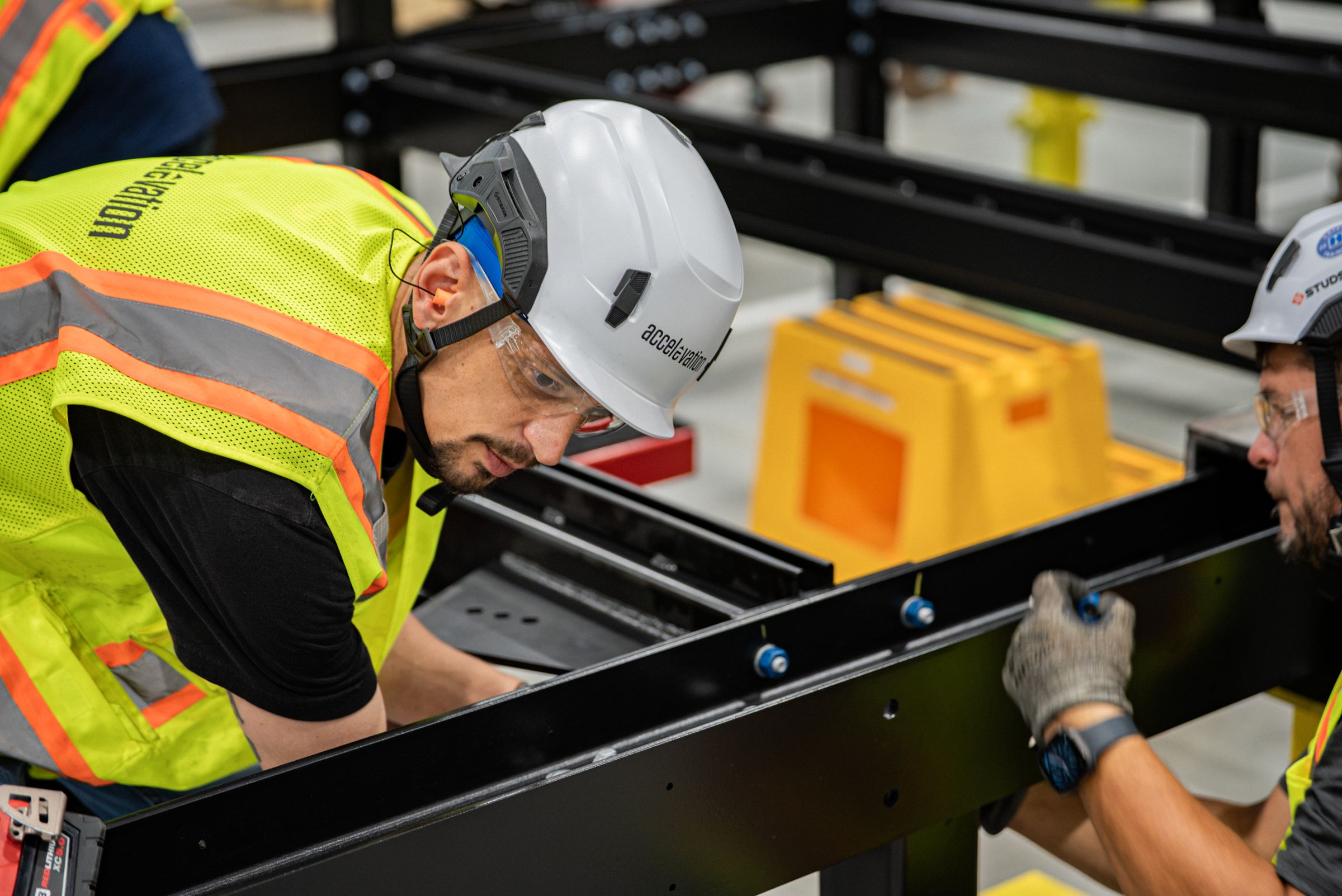 Accelevation technicians inspecting a fabricated steel support structure on the factory floor
