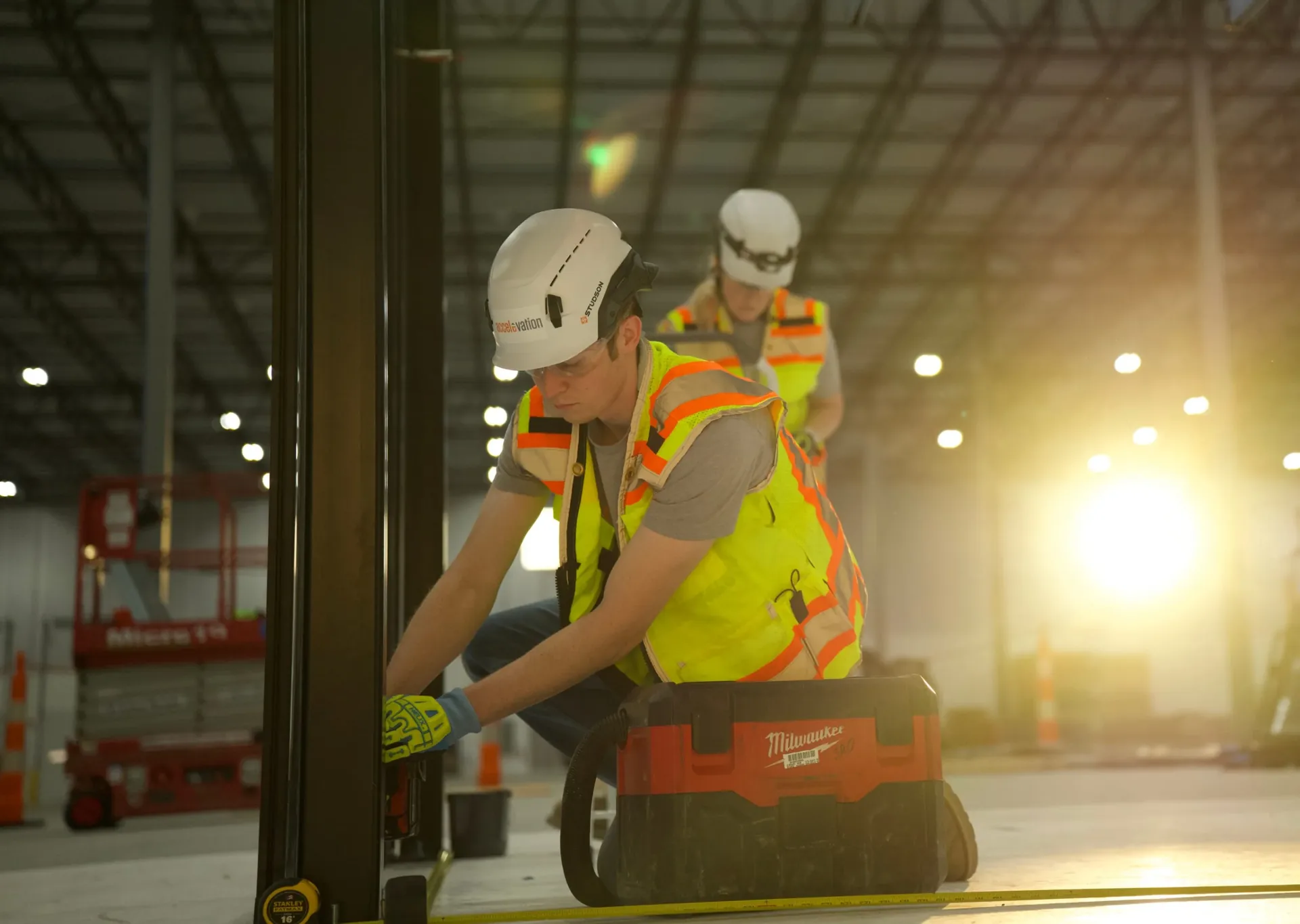 Accelevation workers in hard hats and high-visibility vests inside a manufacturing facility