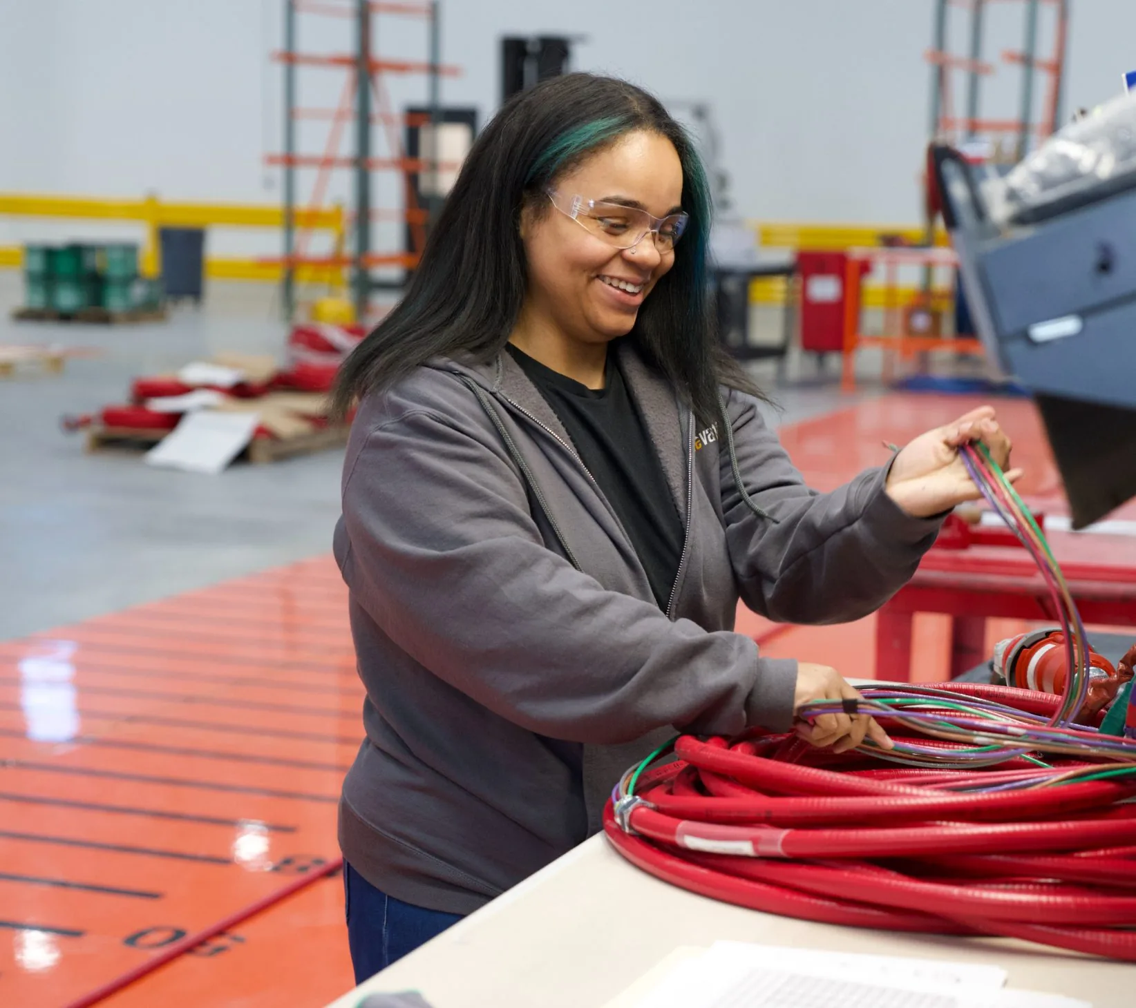 An Accelevation employee coiling red cable assemblies at a workbench