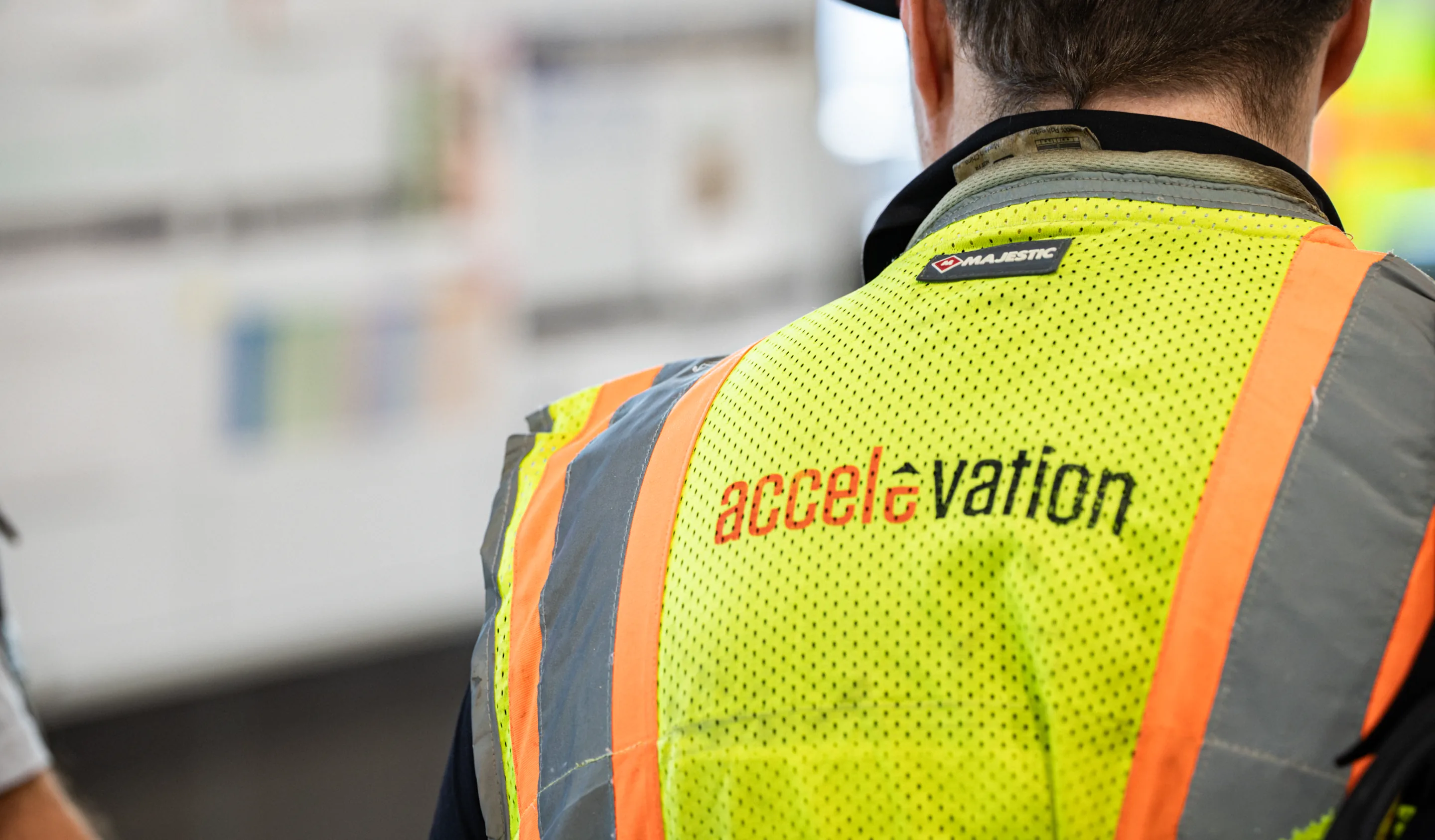 Worker wearing an Accelevation branded high-visibility safety vest on the production floor