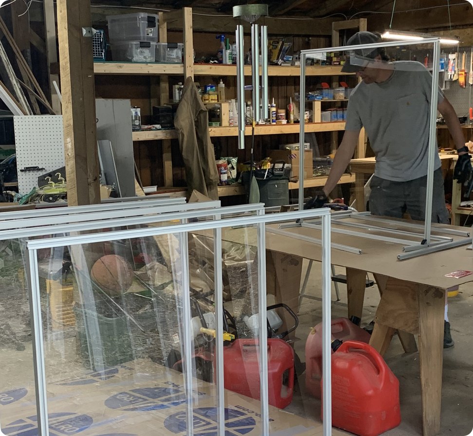 A worker assembling custom clear protective barriers in a workshop