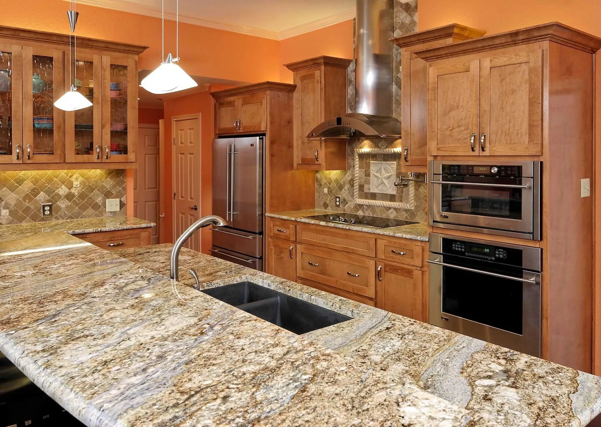 Modern kitchen with granite countertops, wooden cabinets, stainless steel appliances, and dual sinks.