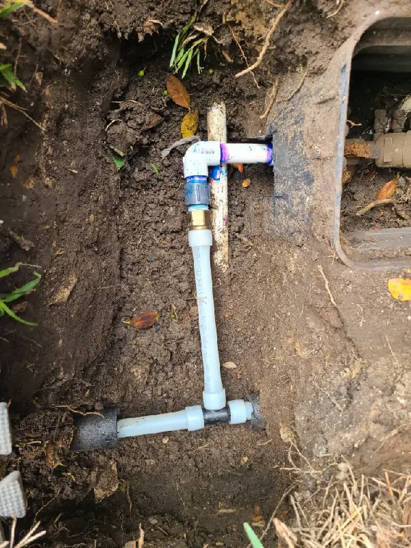 Underground view of PVC piping and fittings for a sewer line installation in soil.