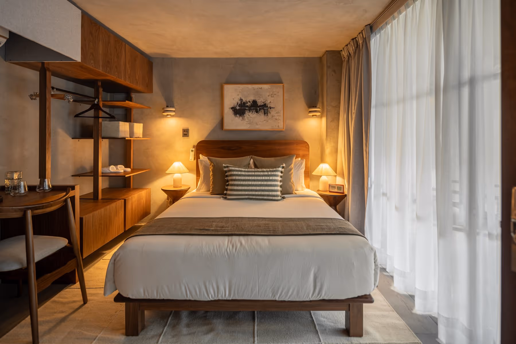 Cozy modern bedroom with wooden furniture, a bed with striped pillow, and soft lighting from lamps.