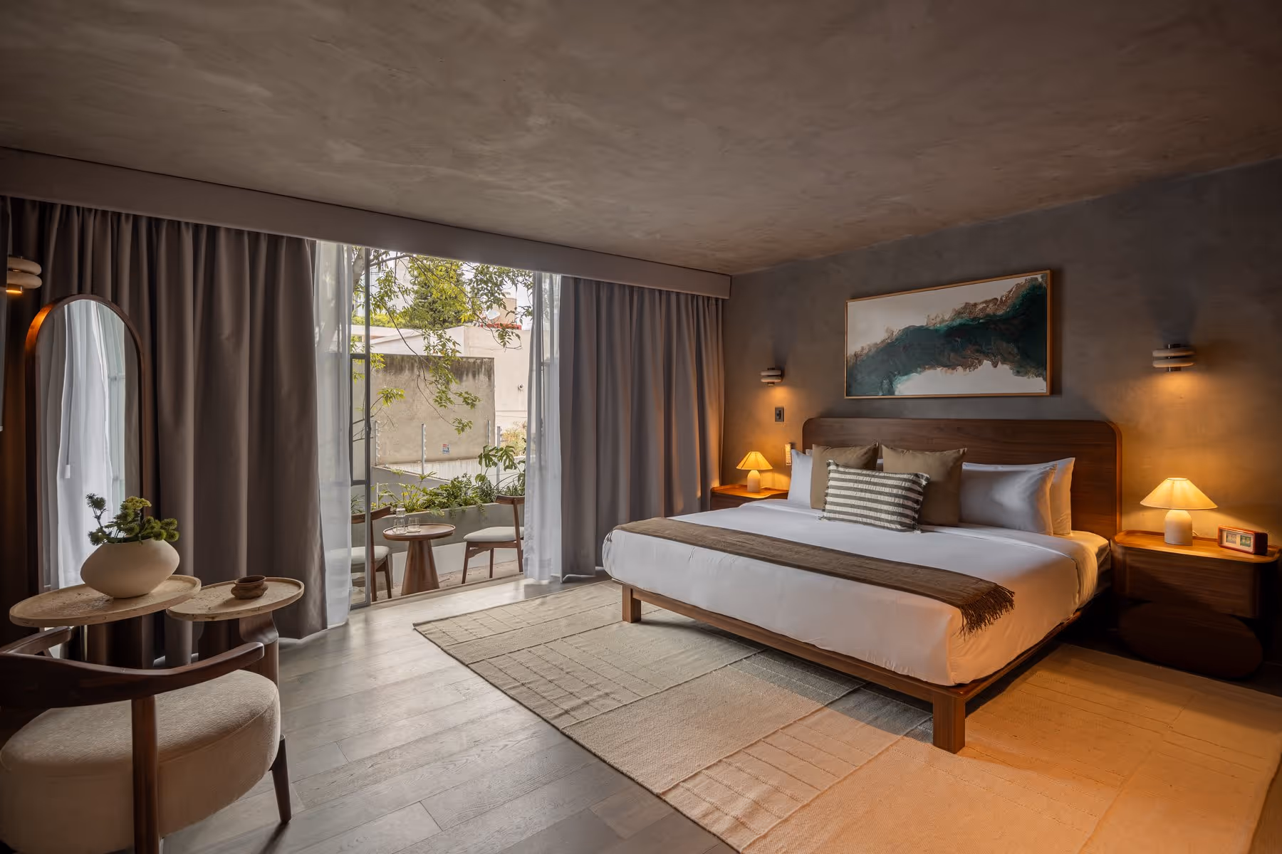 Modern bedroom with a large bed, two bedside lamps, abstract wall art, and a glass door to a terrace.