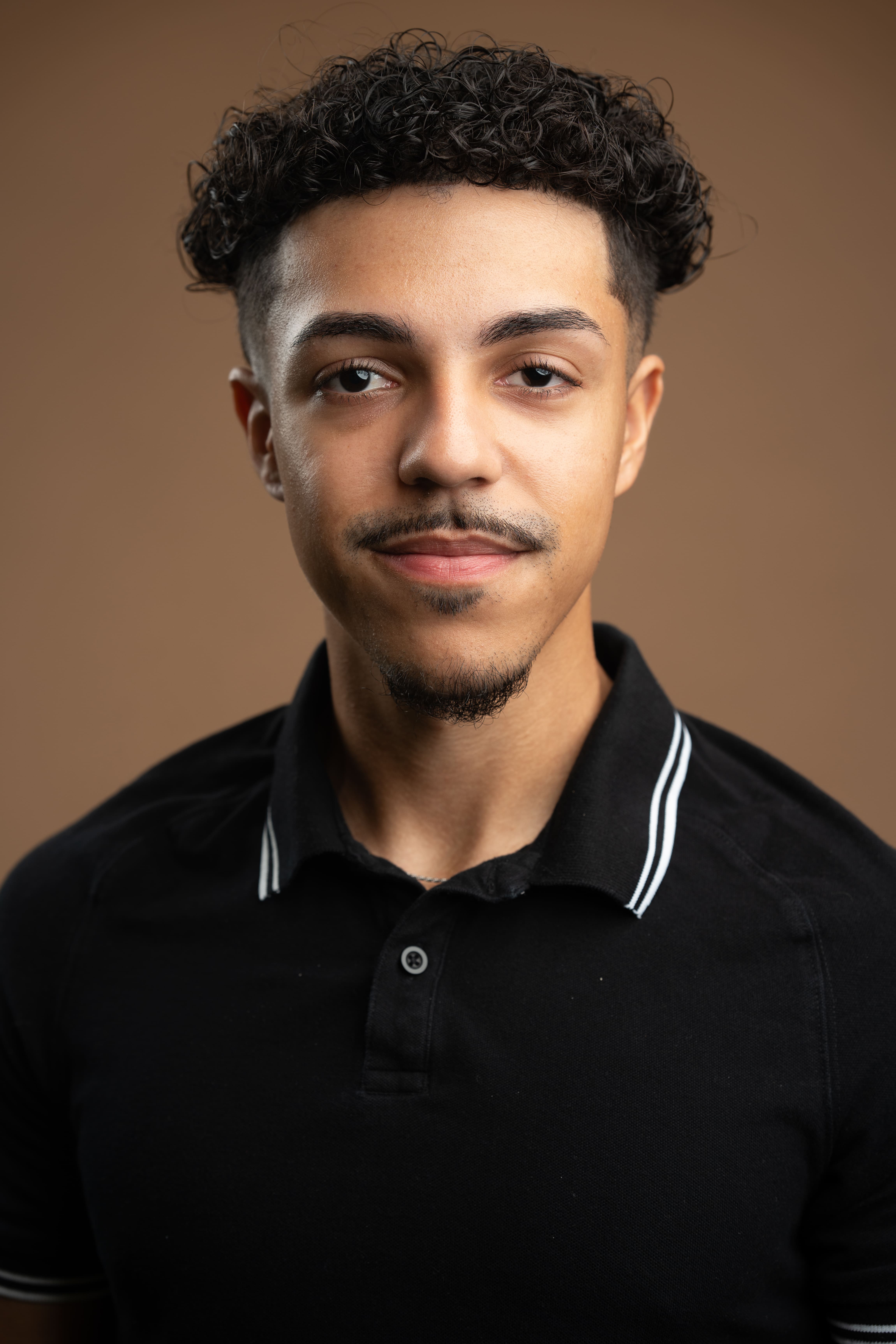Staff headshot of J. Pena wearing a black polo shirt