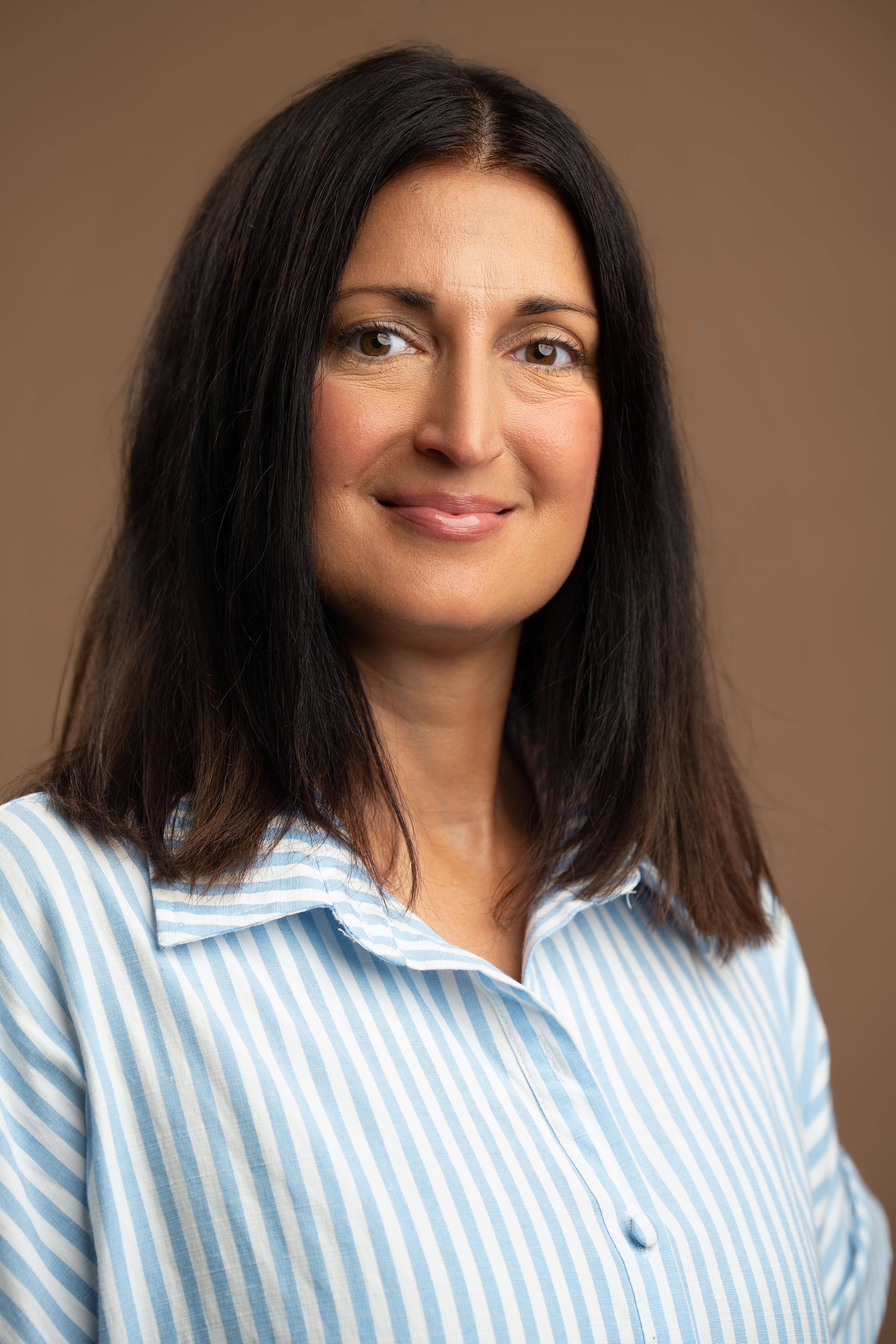 Staff portrait of M Russo smiling against brown background
