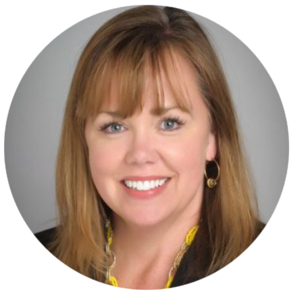 Smiling woman with light brown hair, hoop earrings, and a yellow necklace on gray background.