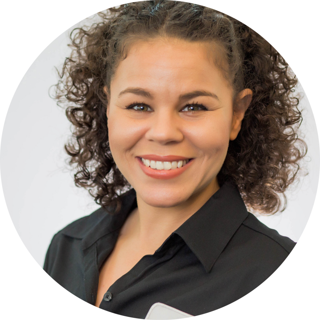 Smiling woman with curly hair wearing a black collared shirt against a light background.