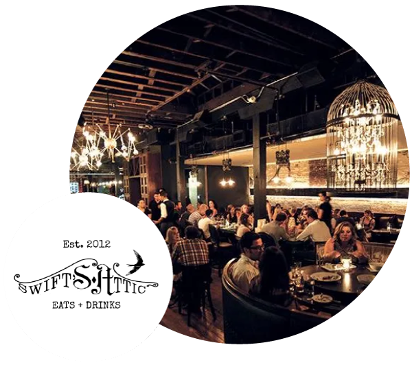 Dimly lit restaurant interior with people dining and a large decorative chandelier birdcage.