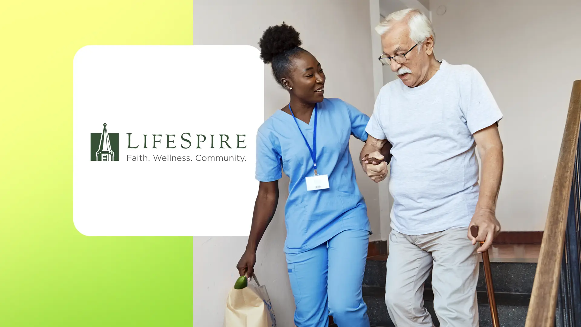 Caregiver in blue scrubs helping elderly man with cane walk down stairs, carrying a grocery bag.